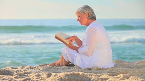 Mature-woman-reading-reading-on-a-beach