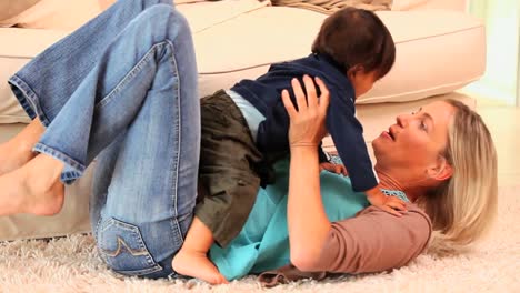 Mother-lying-on-a-carpet-playing-with-her-baby-