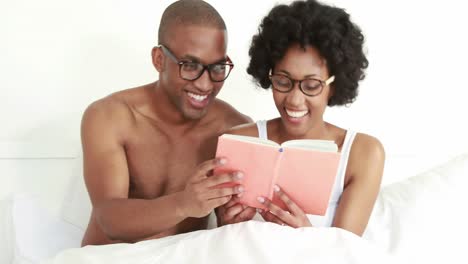 Smiling-young-couple-reading-book-together