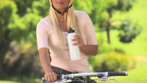Young-woman-taking-a-drink-of-water-while-cycling