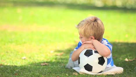 Young-boy-lying-on-the-grass-with-his-ball