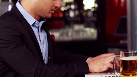 Businessman-having-a-drink-while-working-on-his-laptop