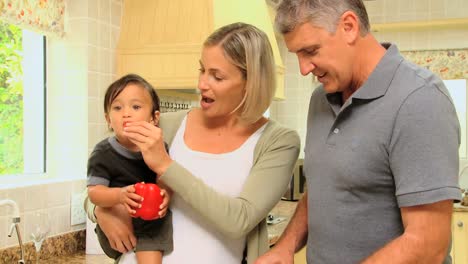 Couple-in-the-kitchen-holding-baby-and-preparing-food