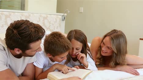 Glückliche-Familie-Auf-Dem-Bett,-Die-Ein-Buch-Liest