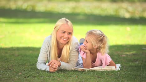 Young-woman-lying-on-the-grass-with-her-daughter-