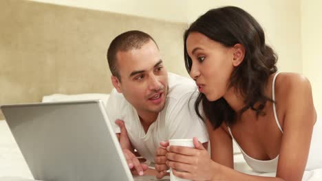 Relaxed-couple-using-laptop-on-bed