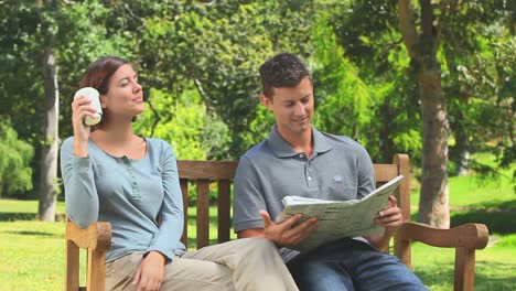 Young-couple-reading-a-newspaper-outdoors