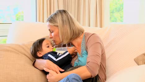 Young-mother-bottlefeeding-baby-on-sofa