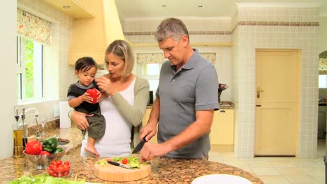 Couple-with-baby-in-kitchen-preparing-vegetables-