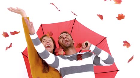Attractive-young-couple-in-warm-clothes-holding-umbrella-and-leaves