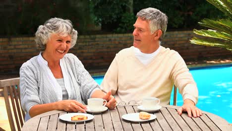 Couple-chatting-over-coffee-by-a-swimming-pool