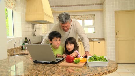 Mann-Und-Seine-Enkelkinder-Folgen-Einem-Rezept-Auf-Einem-Laptop
