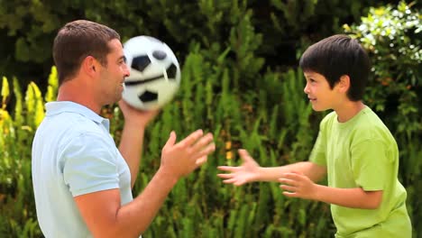 Father-teaching-son-to-head-a-football