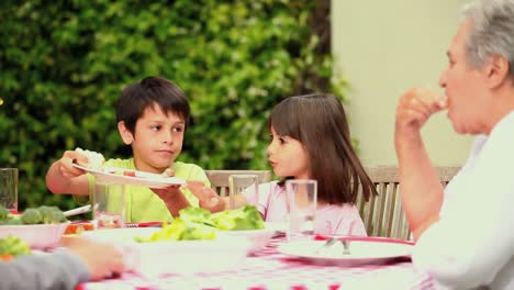 Kinder-Essen-Mit-Ihrer-Familie-Im-Garten