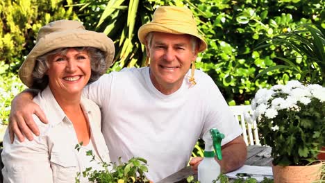 Mature-couple-wearing-sunhats-posing-outdoors-for-a-photo