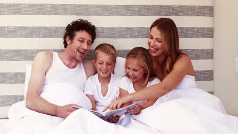 Glückliche-Familie,-Die-Ein-Buch-Auf-Dem-Bett-Liest