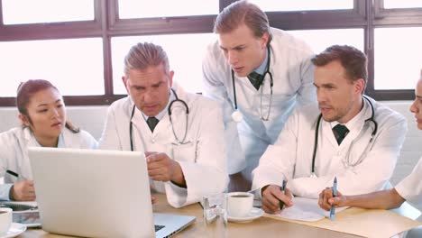 Medical-team-talking-together-while-looking-laptop