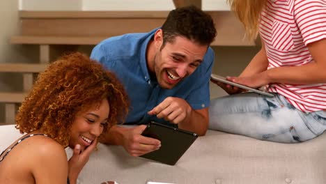 -Cheerful-young-friends-laughing-using-laptop