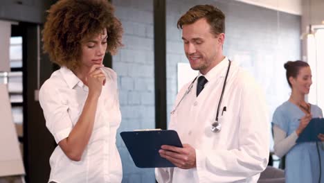Doctor-speaking-with-nurse-while-looking-clipboard