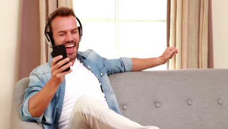 Handsome-man-listening-to-music-and-using-smartphone