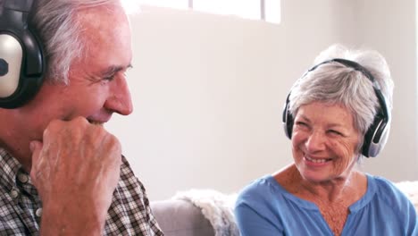 Mature-couple-listening-to-music-with-headphones-on-the-couch