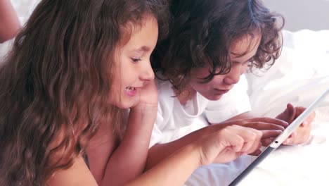 Süße-Geschwister-Benutzen-Tablet-Auf-Dem-Bett-Ihrer-Eltern