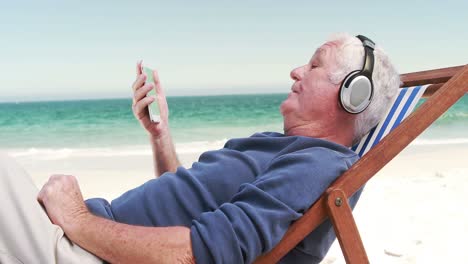 Old-retired-man-listening-music-lying-on-deckchair