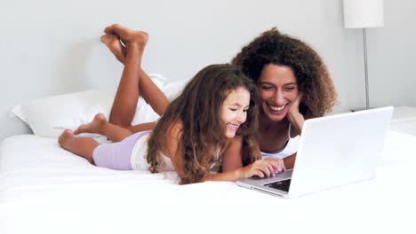 Mother-and-daughter-using-laptop-together-on-their-bed