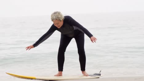 Mature-woman-standing-on-surfboard