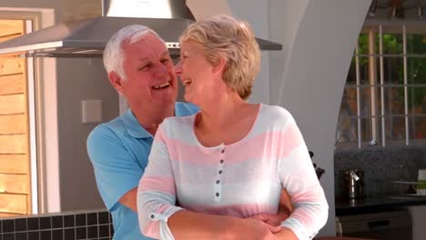 Senior-couple-embracing-in-kitchen