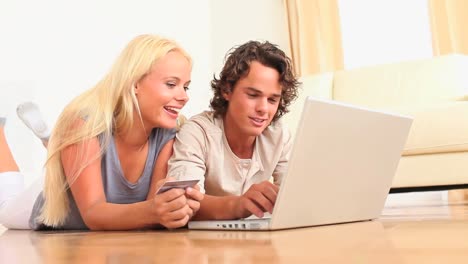 Couple-lying-on-the-floor-with-a-laptop