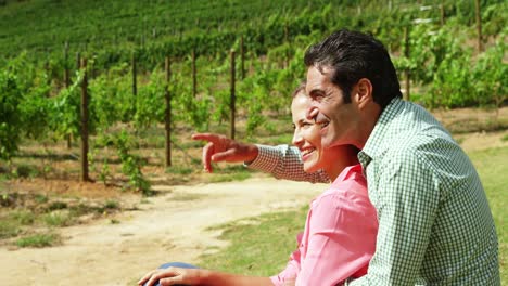 Happy-couple-interacting-while-sitting-in-field