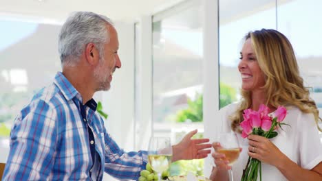 Mature-man-giving-a-bunch-of-roses-to-woman-while-having-breakfast