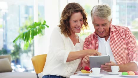 Mature-couple-sitting-on-chair-and-using-digital-tablet