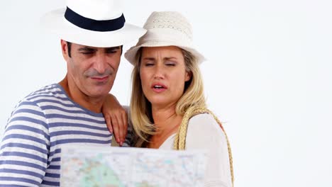 Smiling-couple-looking-at-map-and-pointing-against-white-background