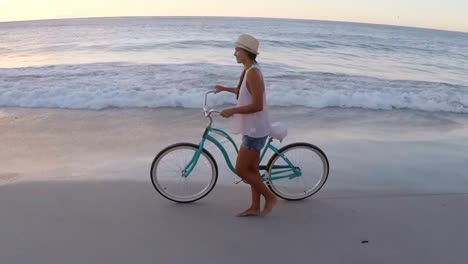 Hermosa-Joven-Caminando-Por-La-Playa-Con-Una-Bicicleta.