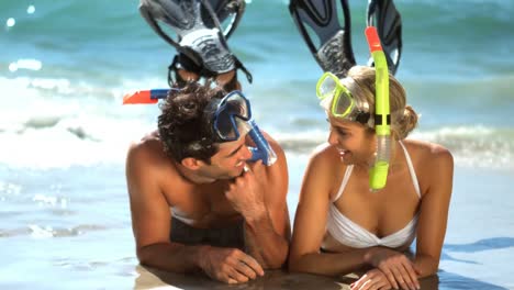 Young-couple-wearing-diving-mask-lying-on-beach