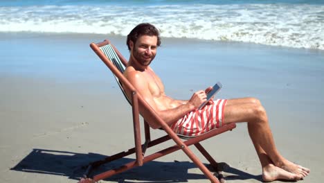 Young-man-sitting-on-armchair-at-beach