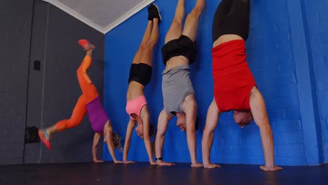 Fitness-trainer-assisting-people-to-perform-handstand