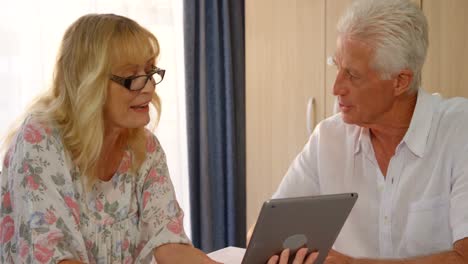 Glückliches-älteres-Paar,-Das-Auf-Ein-Digitales-Tablet-Schaut-Und-Diskutiert
