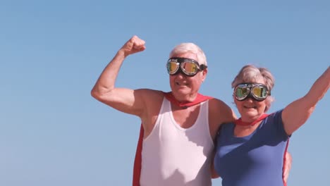senior-couple-flexing-arms-on-the-beach-