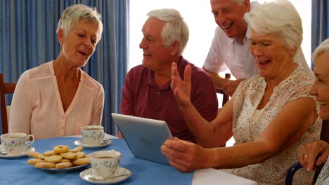 Gruppe-Glücklicher-älterer-Freunde,-Die-Auf-Ein-Digitales-Tablet-Schauen-Und-Lachen