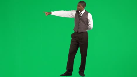 Ethnic-businessman-pointing-next-to-him-against-green-screen