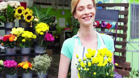 Female-florist-holding-bunch-flowers-in-flower-shop