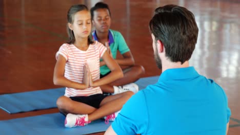 School-kids-and-teacher-meditating-during-yoga-class
