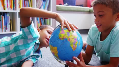 Schoolkids-looking-at-globe-in-library-at-school