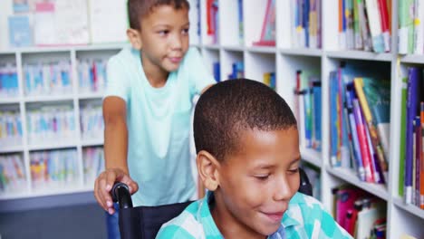 Happy-schoolboy-carrying-his-friend-in-wheelchair-at-library