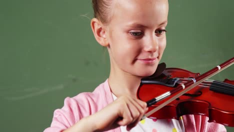 Schoolgirl-playing-violin-in-classroom-at-school