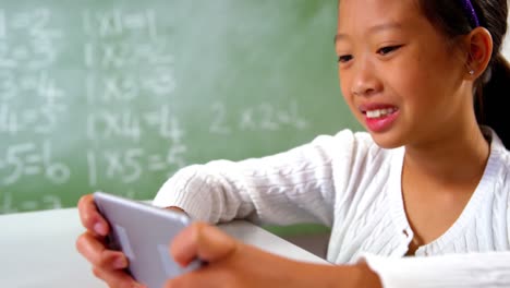 Schoolgirl-using-mobile-phone-in-classroom-at-school