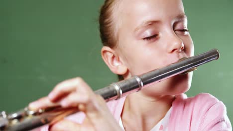 Schoolgirl-playing-flute-in-classroom-at-school